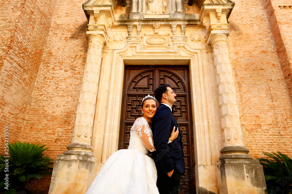 Beautiful bride embracing groom in front of old building