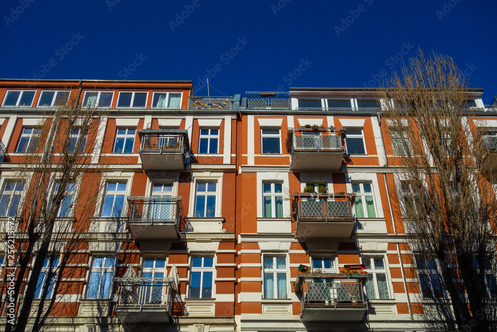 high contrasted picture of apartment house in berlin with brick facade and white ornaments