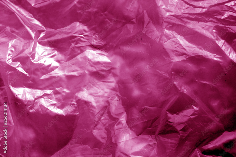 Obraz premium Crumpled transparent plastic surface in pink tone.