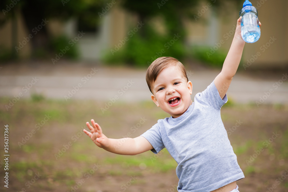joyful child drinks clear water from a bottle on a sunny day in nature joyful child drinks clear water from a bottle on a sunny day in nature