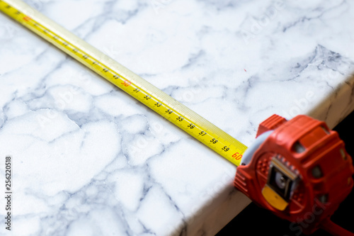 Tape measure to measure the length, lying on the table top.
