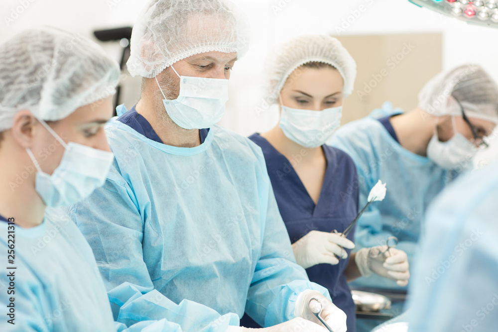 Team of surgeons performing surgery in operation room Team of surgeons performing surgery in operation room