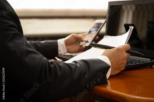 Businessman working on documents paper using cell phone and laptop.