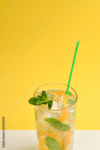 Cocktail with lemon and mint on a yellow background. Copy space.