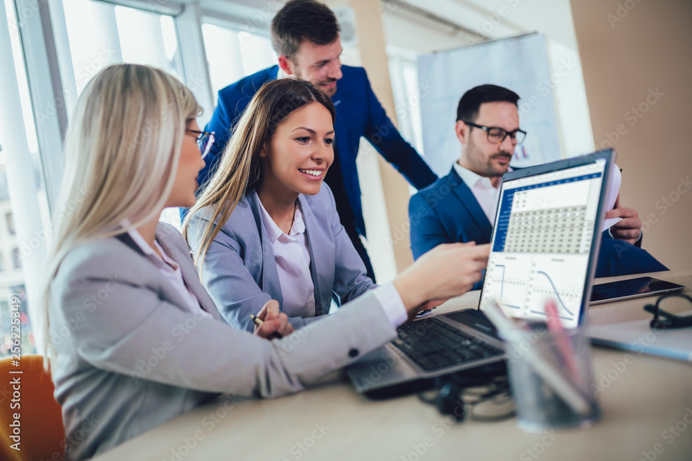 Group of young business people working and using laptop while sitting at the office desk together. Selective focus. Group of young business people working and using laptop while sitting at the office desk together. Selective focus.