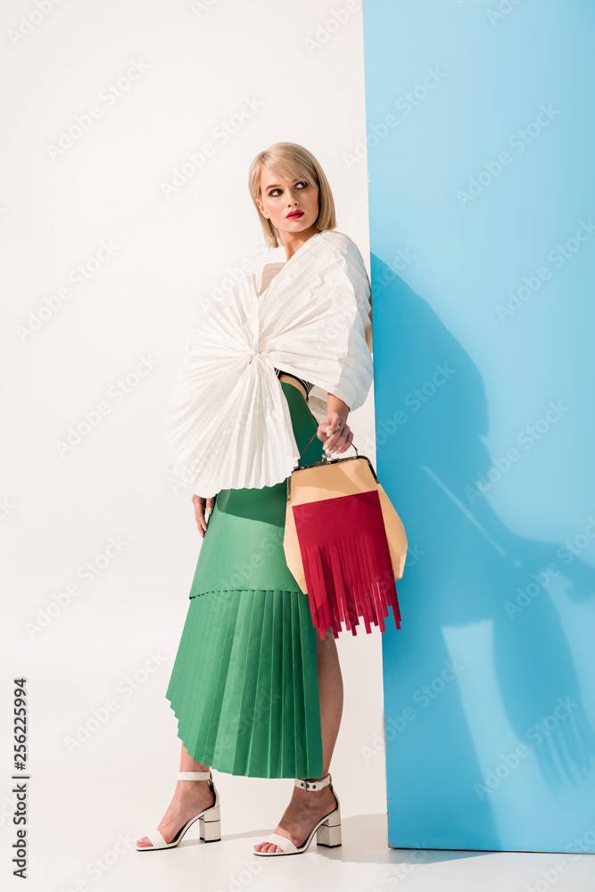 beautiful stylish girl in paper clothes holding paper purse and posing on blue and white beautiful stylish girl in paper clothes holding paper purse and posing on blue and white