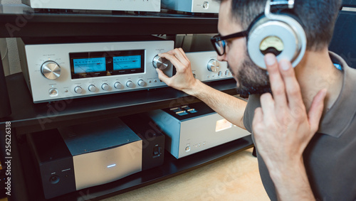Man turning up the volume on home Hi-Fi stereo photo