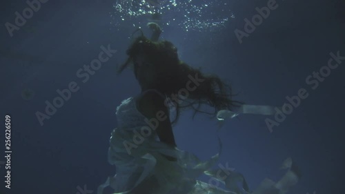 Girl in a white dress with ribbons under the water