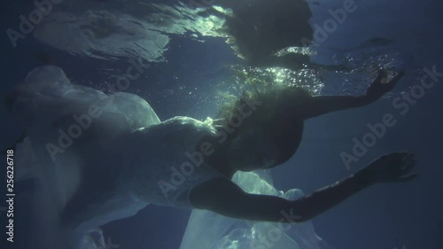 Girl in a white dress with ribbons under the water