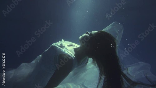 Girl in a white dress with ribbons under the water