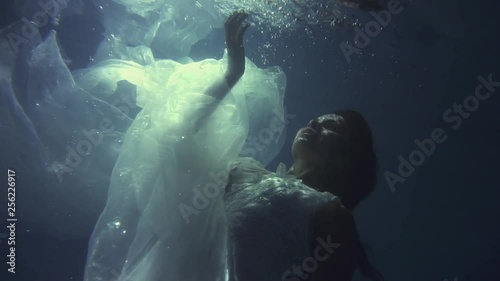 Girl in a white dress with ribbons under the water