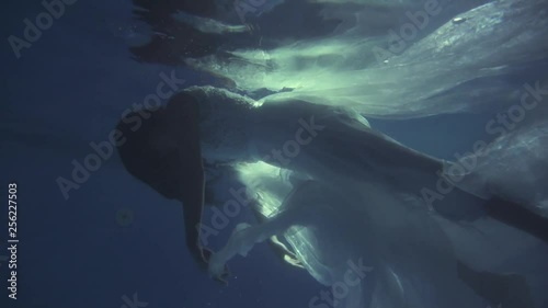 Girl in a white dress with ribbons under the water