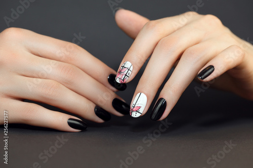 Nails  Art Design. Hands With Manicure On black Background. Close Up Of Female Hands With Trendy pink Nails with spring flower. 