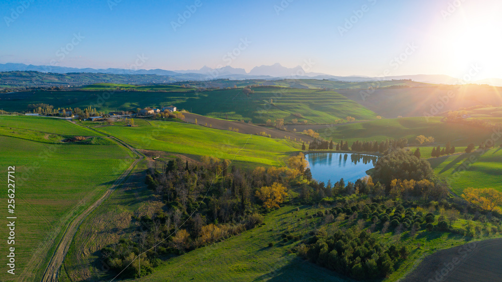 aerial view of a lake and hills landscape at sunset surrounded by agricultural fields