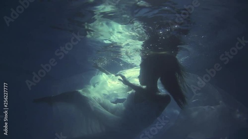 Girl in a white dress with ribbons under the water