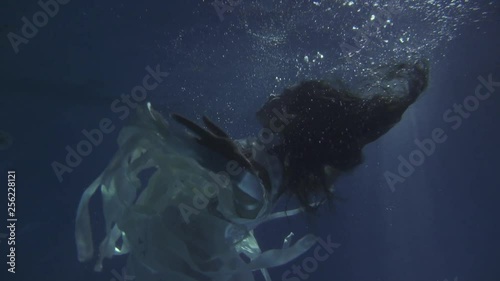 Girl in a white dress with ribbons under the water