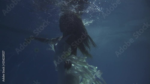 Girl in a white dress with ribbons under the water