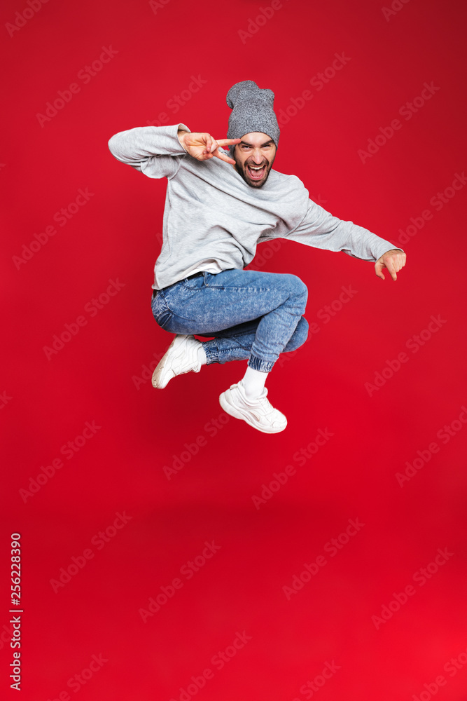 Full length photo of beautiful man smiling and jumping isolated over red background Full length photo of beautiful man smiling and jumping isolated over red background