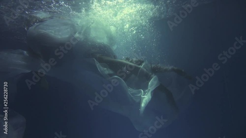 Girl in a white dress with ribbons under the water