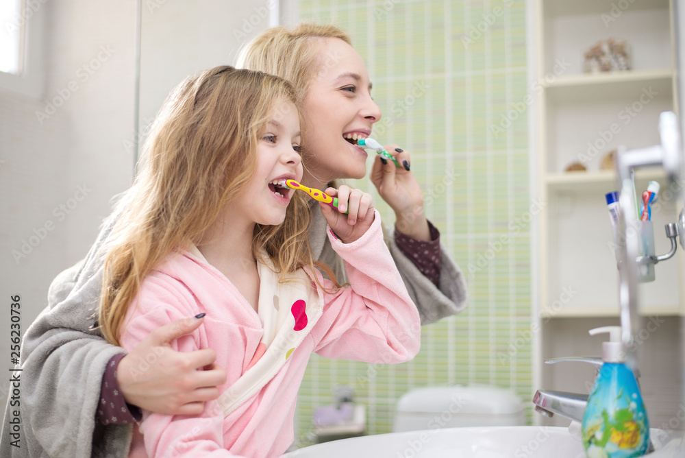 Happy family mother and child girl cleans teeth with toothbrush Happy family mother and child girl cleans teeth with toothbrush