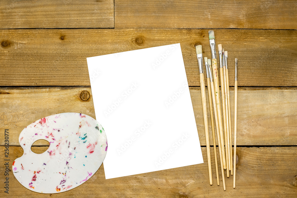 Paint brushes and dirty pallet on a rustic distressed wooden background Paint brushes and dirty pallet on a rustic distressed wooden background