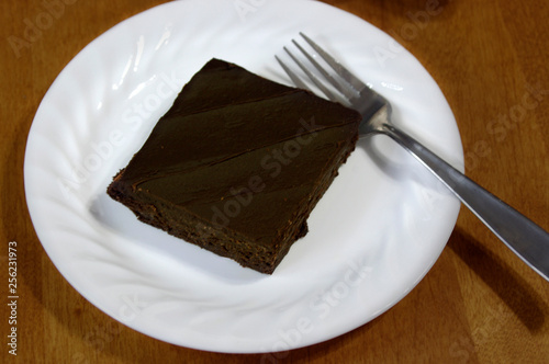 Rich chocolate brownie on white plate with fork