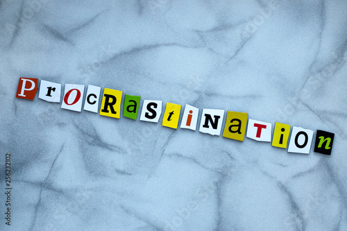 Word procrastination of cut letters on gray background. Psychologic concept. Headline - procrastination. A word writing text procrastination. Abstract card with an inscription procrastination on grey  photo