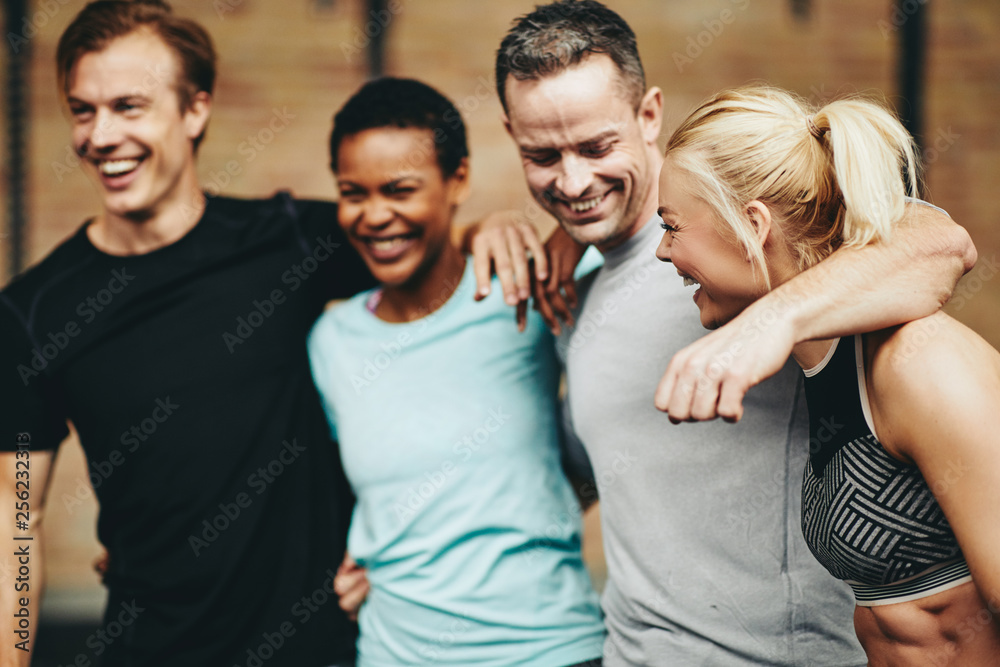 Friends laughing after a workout together in a gym Friends laughing after a workout together in a gym