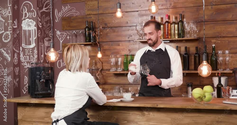 Bartender telling a story to his coworker after work. Restaurant employees socialise after a busy day. Bartender telling a story to his coworker after work. Restaurant employees socialise after a busy day.