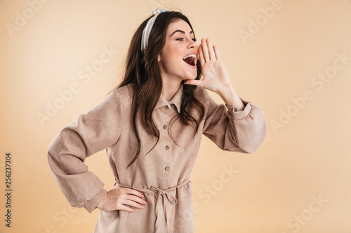 Beautiful excited young pretty woman posing isolated over beige background wall screaming.