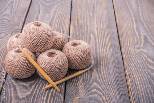 Balls of yarn and knitting needles for knitting on a wooden background.
