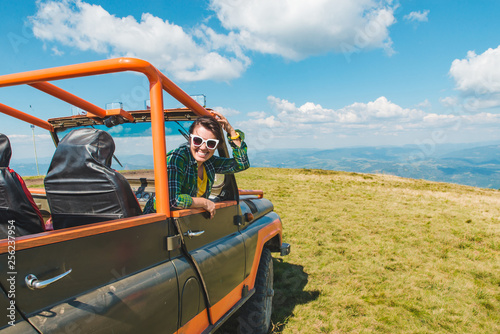 woman in off road cur at the top of the mountain. beautiful view on background. copy space