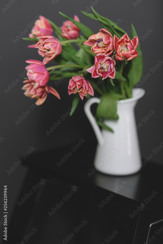 A bouquet of pink peony tulips in a white jug. A bouquet of pink peony tulips in a white jug.