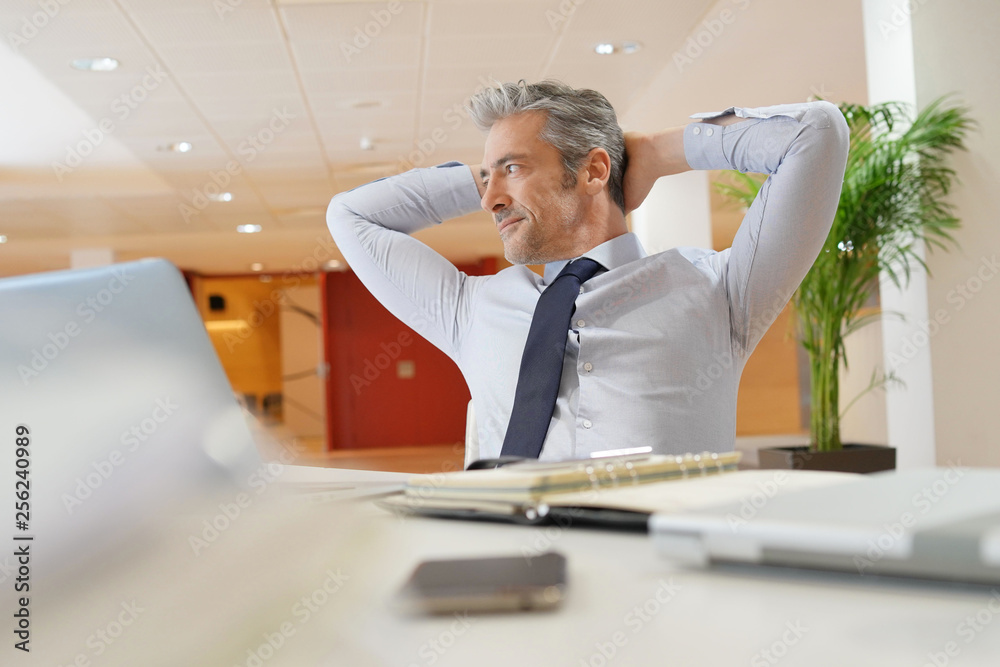 Fototapeta premium Mature businessman relaxing at desk in office