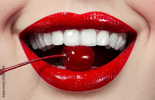 Red lips close-up with bright red cherries at the mouth. beautiful white teeth.