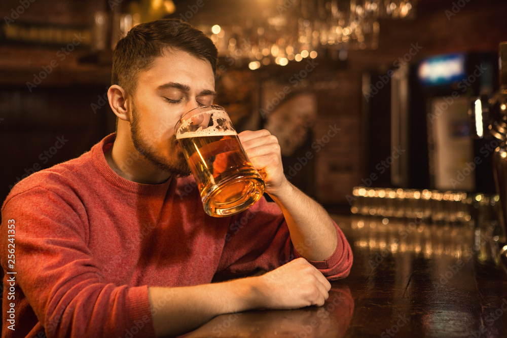 Young man enjoying drinking beer at the pub