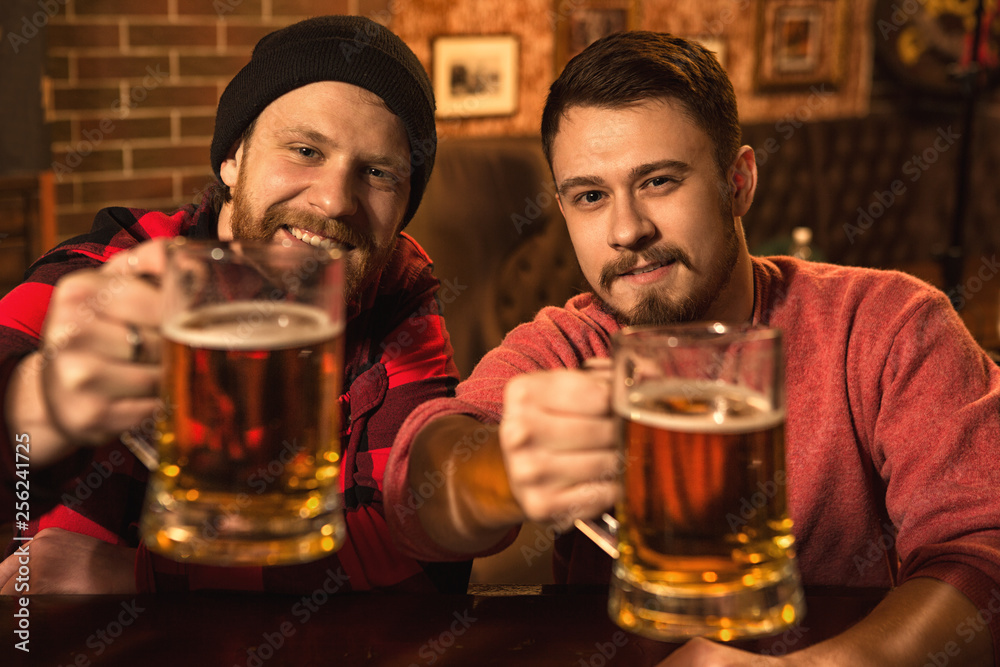 Happy male friends enjoying beer together at the bar