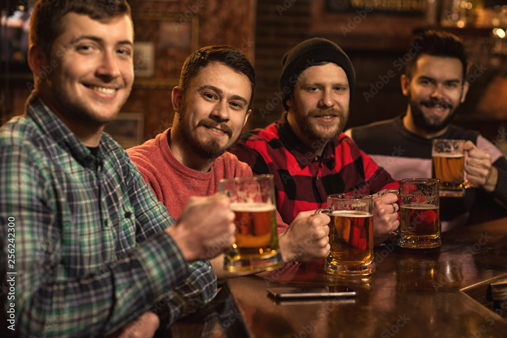 Happy male friends enjoying beer together at the bar