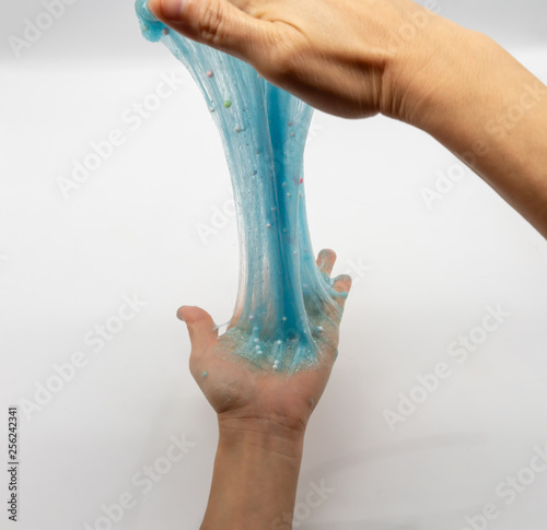 Hand strecthing transparent blue glitter slime isolated on white photo