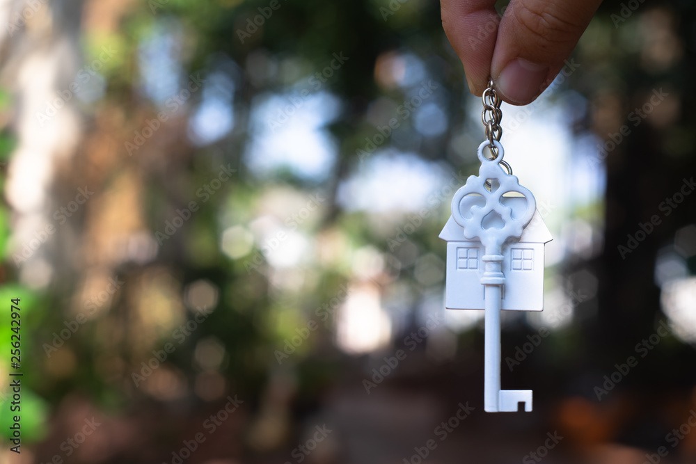 Hanging home key with house keyring with green garden background