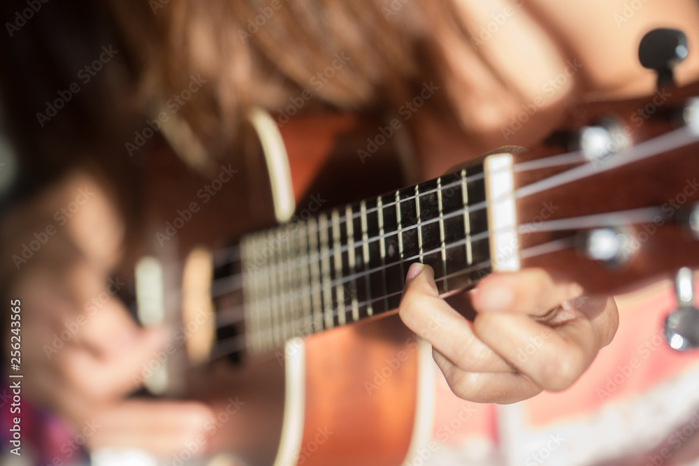 Fototapeta premium Women playing ukulele music with light of sun