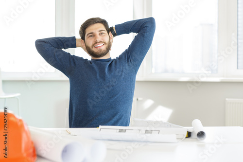 Cheerful young businessman relaxing at his workplace