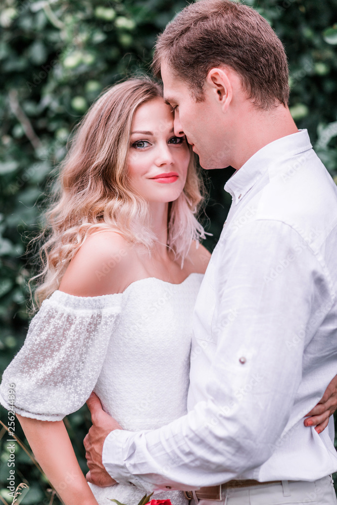 Fototapeta premium Bride and groom with a bouquet of peonies posing against the backdrop of the forest
