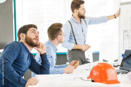 Young male architect looking bored during business meeting