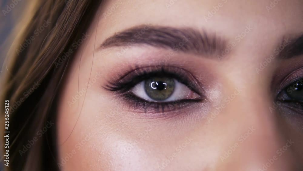 Closeup macro portrait of female face. Young girl with green eyes with beautiful makeup and long black eyelashes. Girl with perfect skin and freckles open her eyes Closeup macro portrait of female face. Young girl with green eyes with beautiful makeup and long black eyelashes. Girl with perfect skin and freckles open her eyes