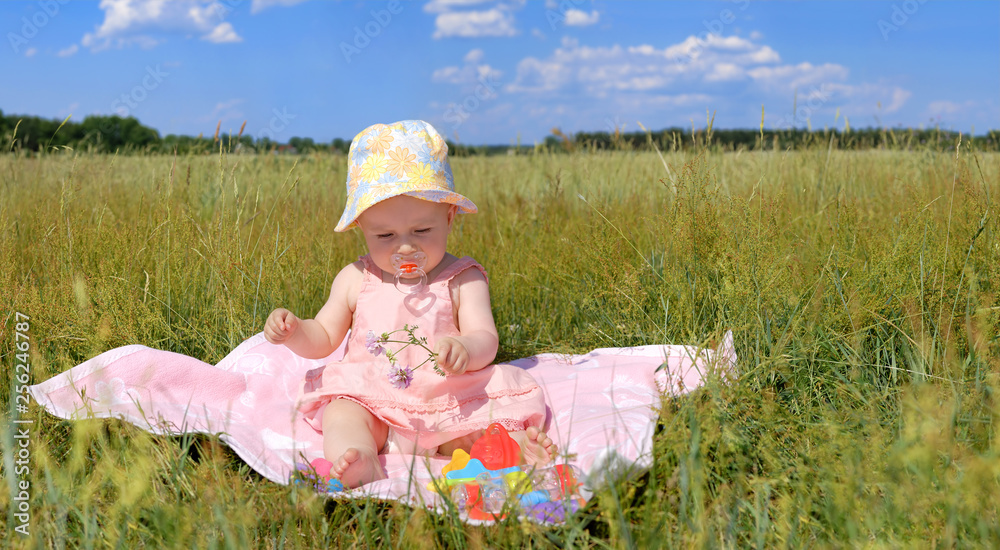 Panorama, little girl in a hat sitting on green field Panorama, little girl in a hat sitting on green field