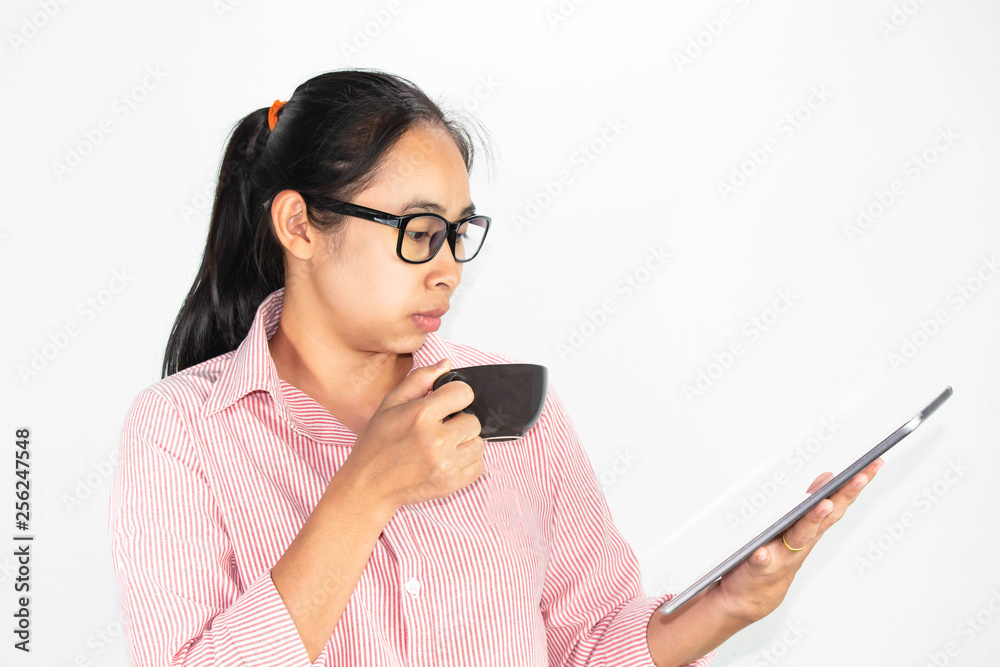 Close up portrait of confident Asian woman, wearing glasses and holding coffee cup, looking tablet with looking seriously face, standing over white background with copy space. Close up portrait of confident Asian woman, wearing glasses and holding coffee cup, looking tablet with looking seriously face, standing over white background with copy space.