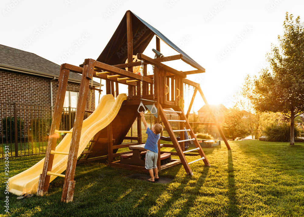 Boy playing with jungle gym in backyard during sunset Boy playing with jungle gym in backyard during sunset