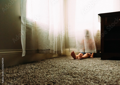 Boy hiding behind curtain at home