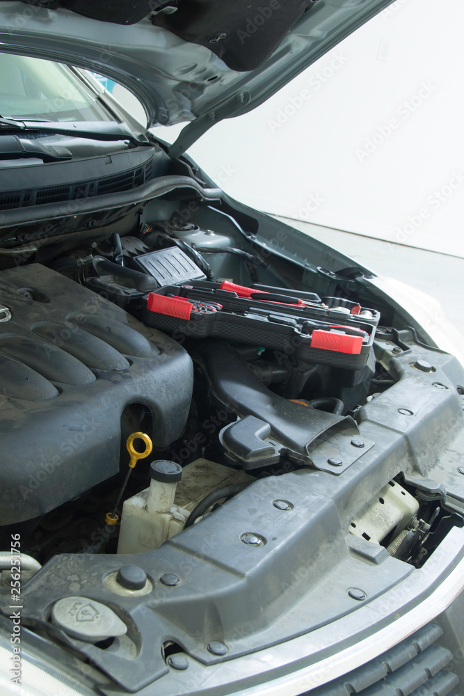 Performing car repait in a home garage to provide safe transportation . Performing car repait in a home garage to provide safe transportation .
